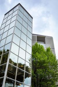 un edificio de cristal con un árbol delante de él en Villa Regina - MarePineta Resort, en Milano Marittima