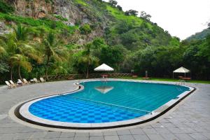 a large blue swimming pool in front of a mountain at Aaram Baagh - A Luxury Nature Resort in Udaipur