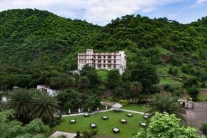 a large building in the middle of a green hill at Aaram Baagh - A Luxury Nature Resort in Udaipur