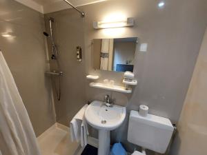 a bathroom with a sink and a toilet and a mirror at Logis Hotels - Le Saint Clément - Hotel Restaurant in Saint-Médard-de-Guizières