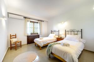 a bedroom with two beds and a chair at Villa Marlis in Port des Torrent