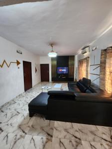 a living room with a black couch and a television at CG Apartments in Ikeja