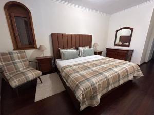 a bedroom with a bed and a chair and a mirror at Casa Monte da Volta in Chaves