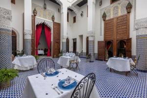 uma sala de jantar com mesas e cadeiras num edifício em Palais Nazha Fes - Luxury Lodging em Fez