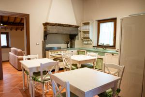 a kitchen with white tables and chairs and a stove at B&B Casa del Pietro in Pieve San Giovanni