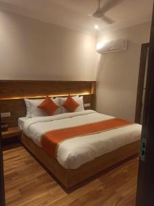 una camera da letto con un grande letto con cuscini arancioni e bianchi di The City Life Hotel a Zirakpur