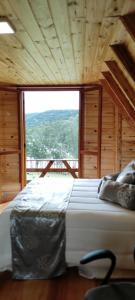 a large bed in a room with a large window at Cabana Santa Cruz in São Francisco de Paula