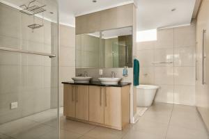 a bathroom with two sinks and a mirror at Hydro Park Residences in Sandton WITH GENERATOR in Johannesburg
