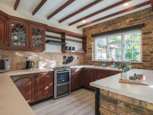 une cuisine avec des placards en bois et un mur en briques dans l'établissement Pass the Keys Spacious Home in Picturesque Village of Wraysbury, à Wraysbury