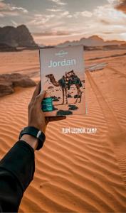 a person holding up a book in the desert at RUM LEONOR CAMP in Wadi Rum