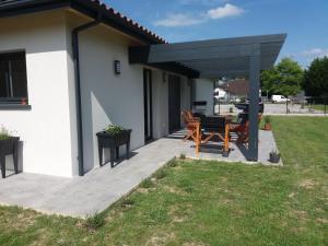 a patio with a black pergola and a table and chairs at Le gite de la battere in Saubusse