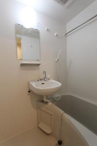 La salle de bains blanche est pourvue d'un lavabo et d'un miroir. dans l'établissement Shibuya Anon #A204, à Tokyo