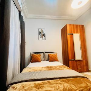 Schlafzimmer mit einem Bett und einem Holzschrank in der Unterkunft Taari's Place in Accra
