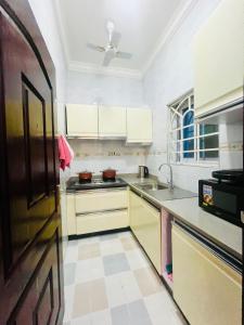 eine Küche mit weißen Schränken und einem Waschbecken in der Unterkunft Taari's Place in Accra