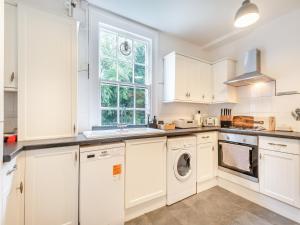a kitchen with white cabinets and a washer and dryer at North Lodge-uk45599 in Southwell