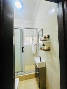 ein Bad mit einem Waschbecken und einem Spiegel in der Unterkunft Taari's Place in Accra
