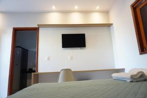 um quarto com uma cama e uma televisão na parede em Pousada Brisas da Natureza em Satuba