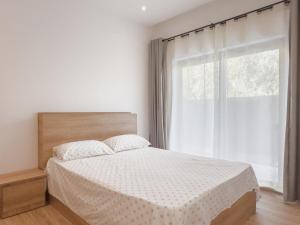 a white bedroom with a bed and a window at Résidence Coastal View - Privilege Appartement in the heart of Grand-Baie in Grand Baie