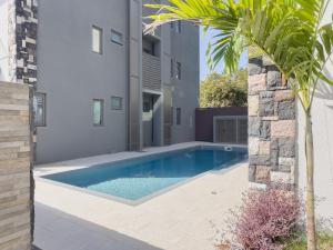 una piscina en medio de una casa en Résidence Coastal View - Privilege Appartement in the heart of Grand-Baie en Grand Baie