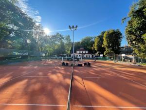 una pista de tenis con bancos. en Włodary Tennis Junior, en Częstochowa