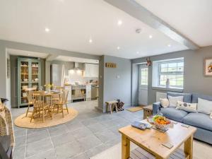 ein Wohnzimmer mit einem blauen Sofa und einem Tisch in der Unterkunft Blackside Cottage in stunning Ayrshire countryside in Mauchline