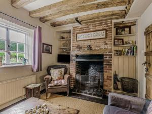 a living room with a brick fireplace with two chairs at Orions Cottage in Chilham