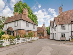 an old house with a white fence in a village at Orions Cottage in Chilham