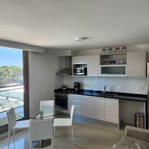une cuisine avec une table en verre et des chaises blanches dans l'établissement Espectacular Monoambiente Nuevo en Place Lafayette piso 7 Punta del Este, à Punta del Este