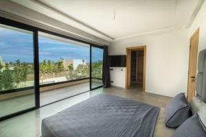 um quarto com uma cama e grandes janelas de vidro em Villa Design à Marrakech em Marrakech