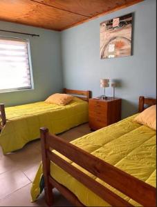 Patio Roma في كويلوتا: غرفة نوم بسريرين مع شراشف صفراء ونافذة