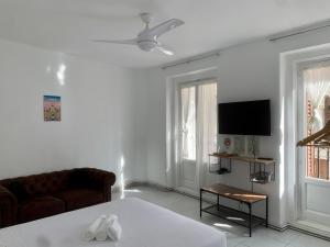 ein weißes Wohnzimmer mit einem Sofa und einem TV in der Unterkunft Gran Via Experience in Madrid