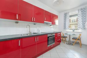 a red kitchen with red cabinets and a table at Stylish Studio for 2 with Balcony Robocza Poznań by Renters in Poznań
