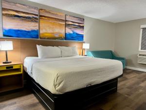 a bedroom with a bed and a blue chair at Days Inn by Wyndham Sarasota I-75 in Sarasota +23 photos
