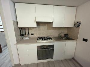 a kitchen with white cabinets and a stove and a sink at Mantellini 2B in Domodossola +8 photos