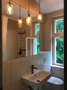 a bathroom with a sink and a toilet and lights at VILLA AM SEE - nähe Berlin in Biesenthal +12 photos