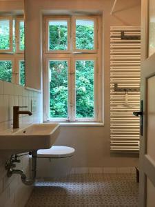 a bathroom with a sink and a toilet and windows at VILLA AM SEE - nähe Berlin in Biesenthal
