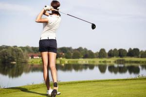 a woman swinging a golf club in front of a lake at VILLA AM SEE - nähe Berlin in Biesenthal