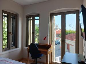 1 dormitorio con escritorio y ventanas con vistas. en Vagia's Home, en Kími