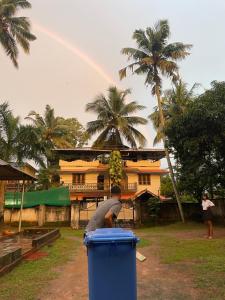 a man standing in a blue trash can with a rainbow in the background at HostelExp, Varkala - A Beach Town Hostel in Varkala