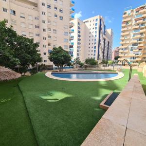 eine Rasenfläche mit einem Pool und Gebäuden in der Unterkunft Apartamento Alcotan I Beach in Cala de Finestrat