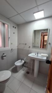 uma casa de banho com um lavatório, um WC e um espelho. em Apartamento Edificio San Francisco em Benidorm