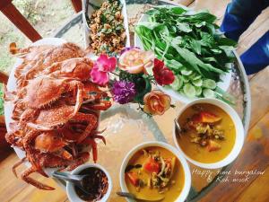a table with a plate of food and bowls of soup at Kohmook Happy time Bungalow in Koh Mook