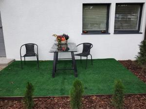 una mesa y dos sillas en un parche de hierba en Pokoje pod Dębem, en Józefów