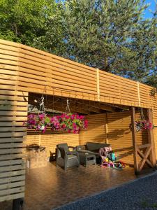 ein Holzgebäude mit einer Terrasse mit Stühlen und Blumen in der Unterkunft Guest house Shulc in Mischhirja