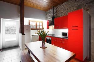 eine Küche mit roten Schränken und einem Holztisch in der Unterkunft Le zihans in Port-de-Lanne