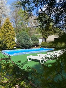 uma piscina com espreguiçadeiras brancas e uma piscina em Guest house Shulc em Mizhhirya