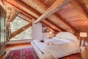 um quarto com uma cama grande num quarto com tectos em madeira em Romito Lodge Apartment Mountain Retreat - Happy Rentals em Cesana Torinese