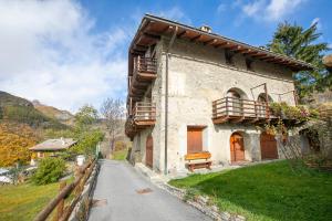 a stone building with wooden balconies next to a road at Romito Lodge Apartment Mountain Retreat - Happy Rentals in Cesana Torinese