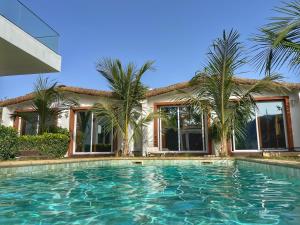 a swimming pool in front of a house with palm trees at Keur Ama in Mbour
