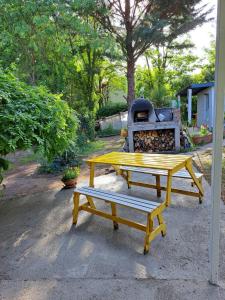 una mesa de picnic amarilla y un banco frente a una estufa en ALOJAMIENTO SERRANO BIS en Villa Giardino